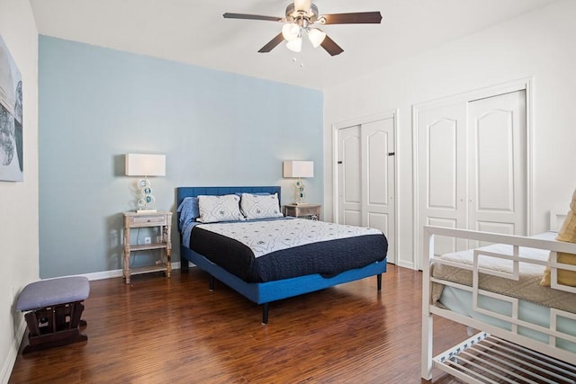 bedroom with multiple closets, ceiling fan, and dark wood-type flooring