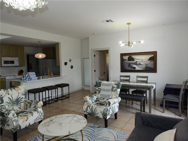 living room with baseboards, light tile patterned flooring, visible vents, and a notable chandelier