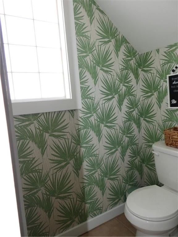 half bathroom featuring baseboards, tile patterned flooring, toilet, and wallpapered walls