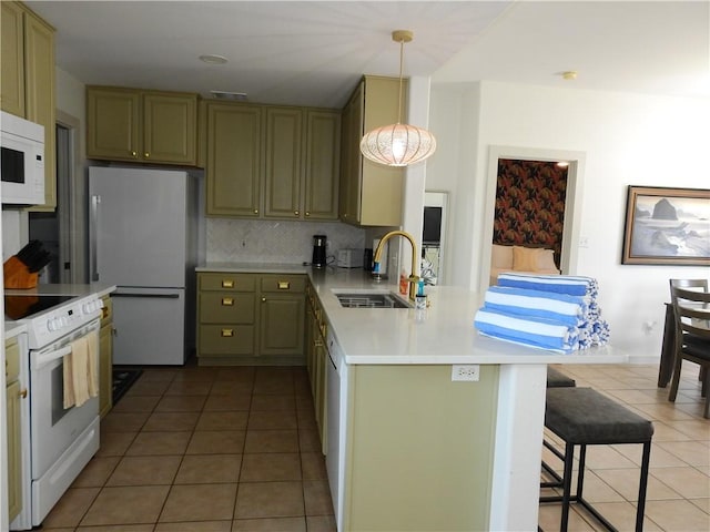 kitchen featuring a peninsula, white appliances, a sink, green cabinets, and decorative light fixtures