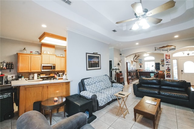 tiled living room with ceiling fan, a raised ceiling, and ornamental molding