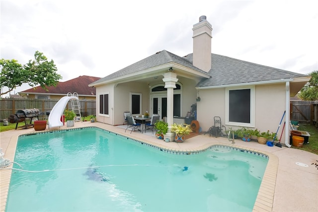 view of swimming pool featuring a water slide and a patio