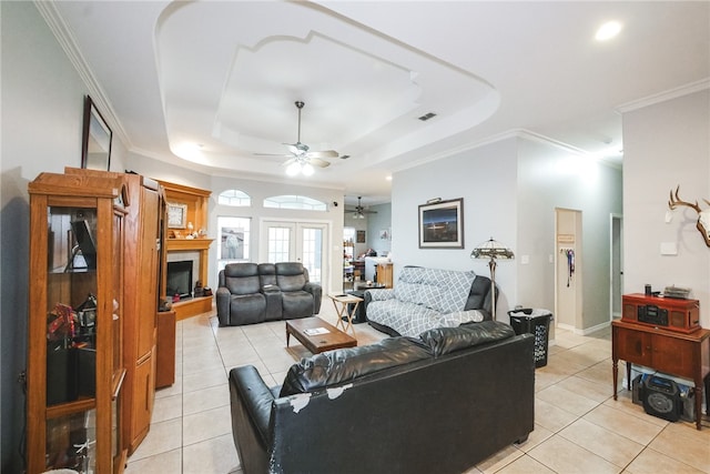 living room with ornamental molding, ceiling fan, a raised ceiling, and light tile patterned floors