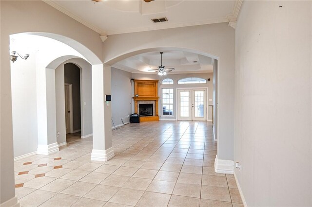 living room with visible vents, arched walkways, ceiling fan, a tray ceiling, and light tile patterned flooring