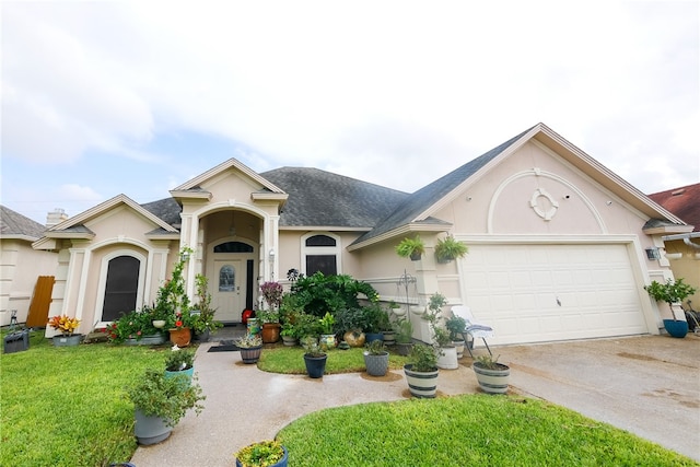 view of front of house featuring a garage, a shingled roof, concrete driveway, stucco siding, and a front yard