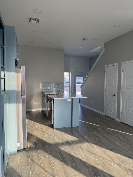 kitchen with wood tiled floor, visible vents, a peninsula, and freestanding refrigerator