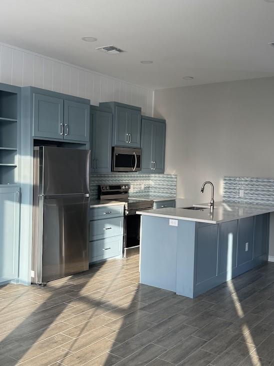 kitchen featuring light countertops, tasteful backsplash, a sink, visible vents, and appliances with stainless steel finishes