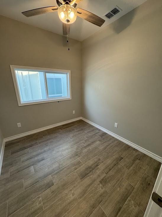 spare room with dark wood-type flooring, baseboards, ceiling fan, and visible vents