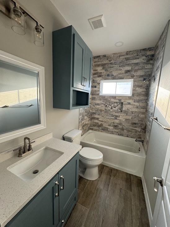 bathroom featuring shower / bathing tub combination, vanity, toilet, visible vents, and wood finished floors