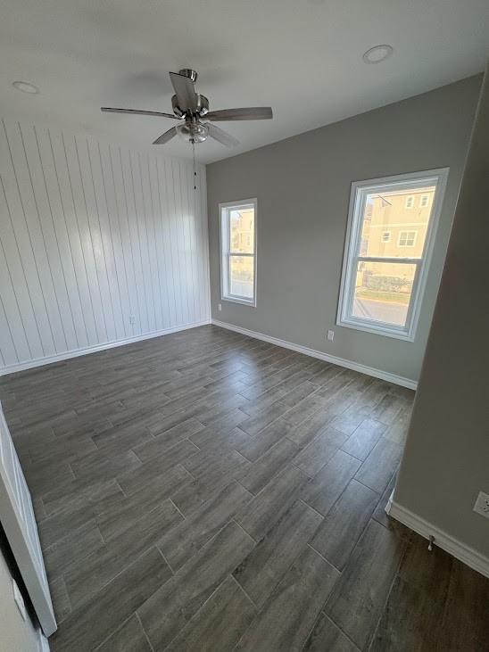 empty room featuring dark wood finished floors, baseboards, and a ceiling fan