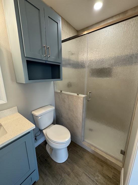 bathroom with toilet, vanity, and a shower stall
