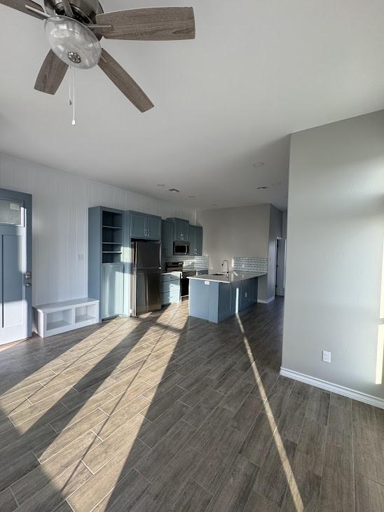 kitchen featuring wood tiled floor, stainless steel microwave, range with electric stovetop, and freestanding refrigerator