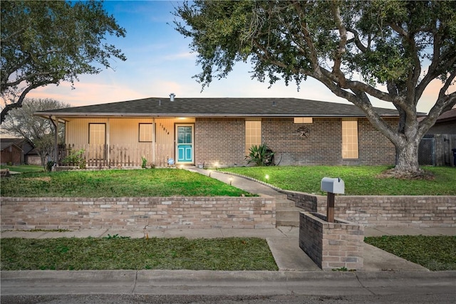 single story home featuring brick siding and a yard