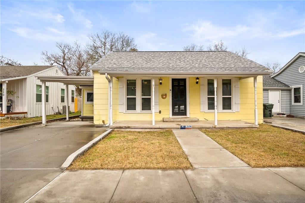 view of front of home with a carport, covered porch, and a front lawn