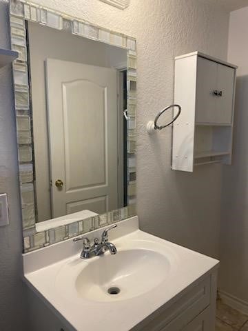 bathroom featuring a textured wall and vanity