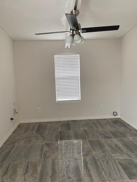 spare room with ceiling fan and baseboards