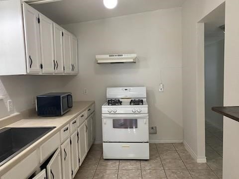 kitchen with black microwave, under cabinet range hood, white cabinetry, gas range gas stove, and light tile patterned flooring