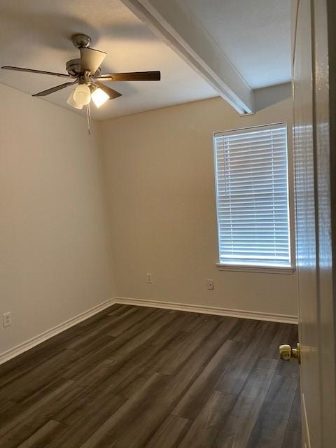 empty room with dark wood-style floors, a ceiling fan, baseboards, and beamed ceiling