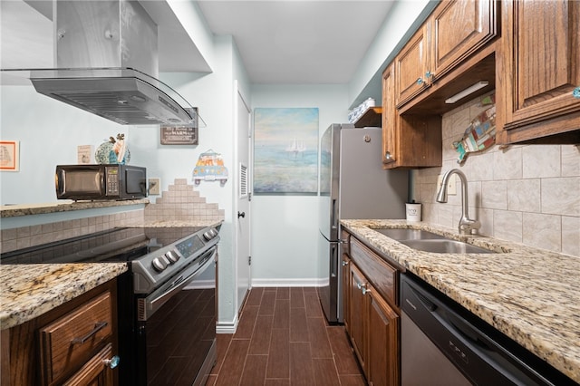 kitchen with appliances with stainless steel finishes, light stone counters, sink, and exhaust hood