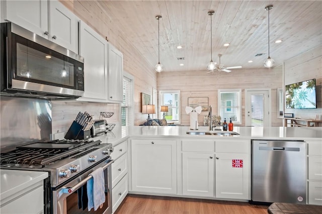 kitchen with pendant lighting, sink, kitchen peninsula, and appliances with stainless steel finishes