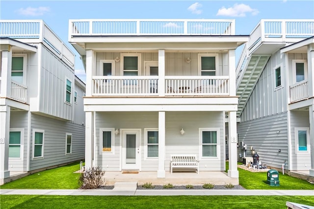 back of house with a lawn and a balcony