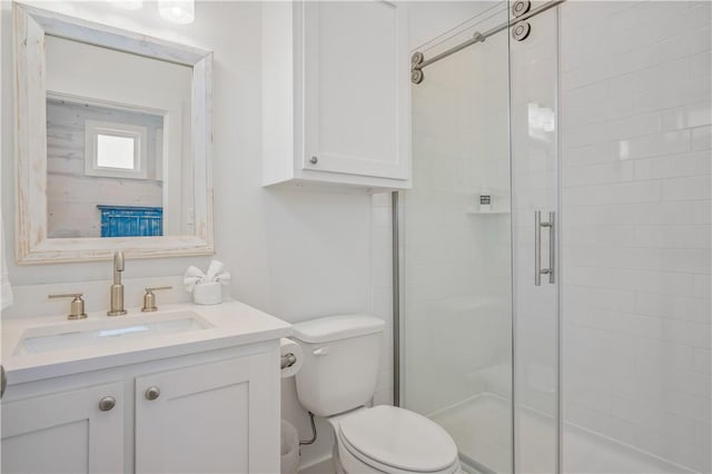 bathroom featuring vanity, toilet, and a shower with shower door