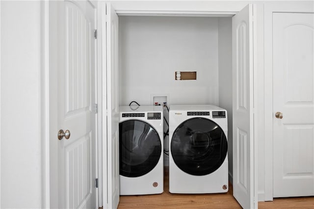 laundry area featuring washing machine and dryer and light wood-type flooring