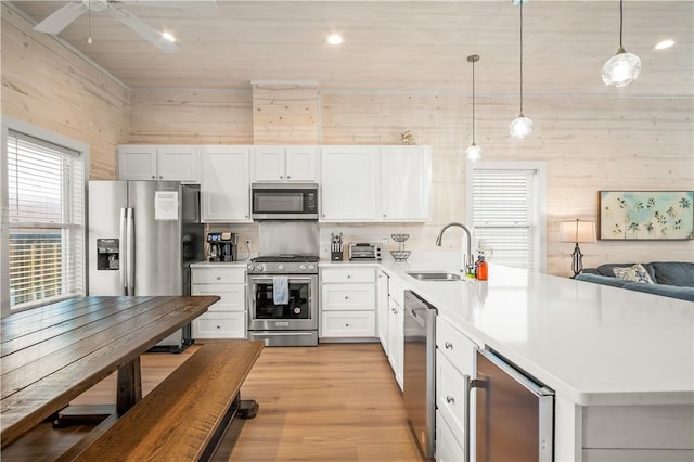 kitchen with pendant lighting, sink, white cabinetry, stainless steel appliances, and wine cooler