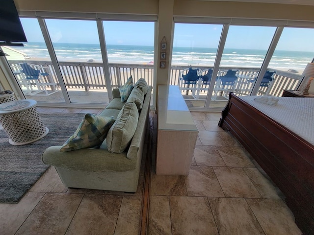 bedroom with access to exterior, a view of the beach, and a water view