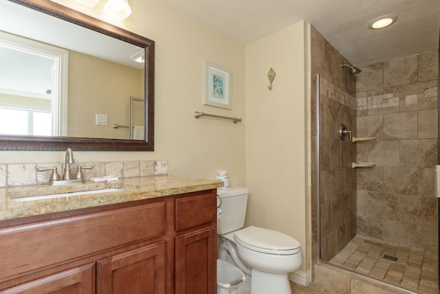 bathroom featuring tiled shower, toilet, and vanity