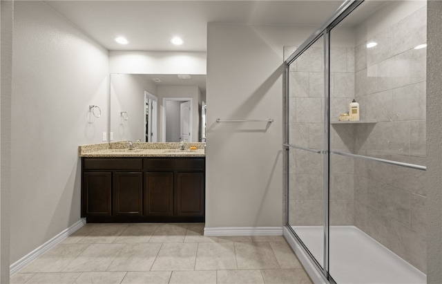 bathroom with a shower with shower door, tile patterned floors, and vanity