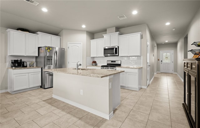 kitchen with sink, white cabinets, light stone counters, a center island with sink, and stainless steel appliances