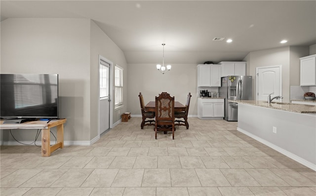 tiled dining area featuring sink, a chandelier, and vaulted ceiling