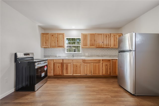 kitchen with decorative backsplash, appliances with stainless steel finishes, sink, and light hardwood / wood-style flooring