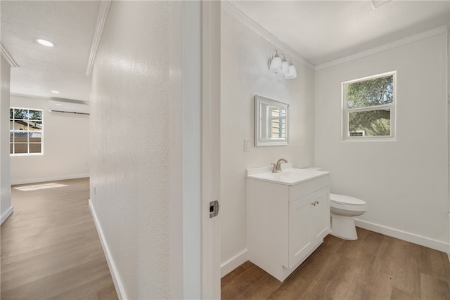 bathroom featuring wood-type flooring, toilet, ornamental molding, vanity, and an AC wall unit