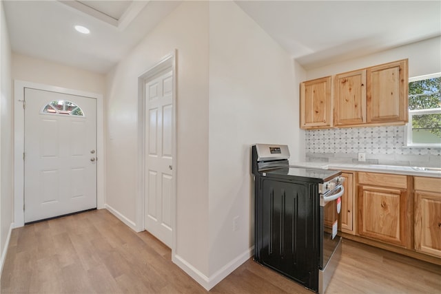 kitchen featuring light wood-type flooring, decorative backsplash, and electric range