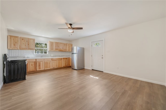 kitchen featuring ceiling fan, backsplash, light brown cabinets, light wood-type flooring, and stainless steel fridge