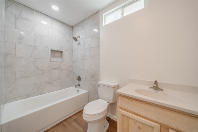 full bathroom featuring hardwood / wood-style floors, vanity, tiled shower / bath combo, and toilet