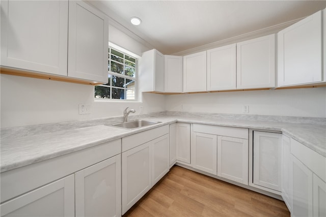 kitchen with white cabinetry, sink, and light hardwood / wood-style flooring