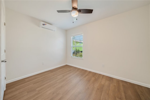 spare room featuring ceiling fan, an AC wall unit, and light wood-type flooring