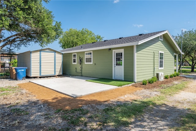 rear view of property featuring a storage unit and a patio area