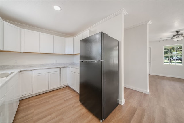 kitchen with white cabinetry, black fridge, ceiling fan, and light wood-type flooring