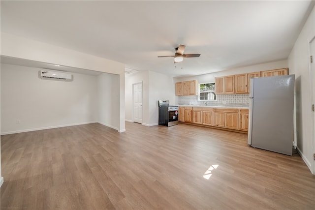 kitchen featuring a wall mounted AC, ceiling fan, stainless steel range oven, white refrigerator, and light wood-type flooring