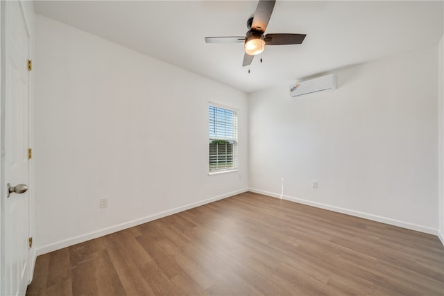 spare room featuring ceiling fan, wood-type flooring, and an AC wall unit