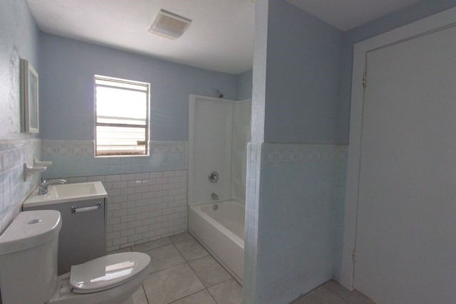 full bathroom with toilet, tile patterned floors, tile walls, washtub / shower combination, and vanity