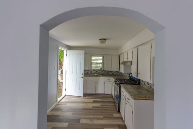 kitchen with hardwood / wood-style flooring, white cabinetry, gas range, and tasteful backsplash