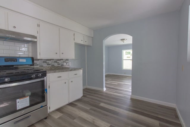 kitchen with light hardwood / wood-style floors, gas range, backsplash, light stone countertops, and white cabinetry