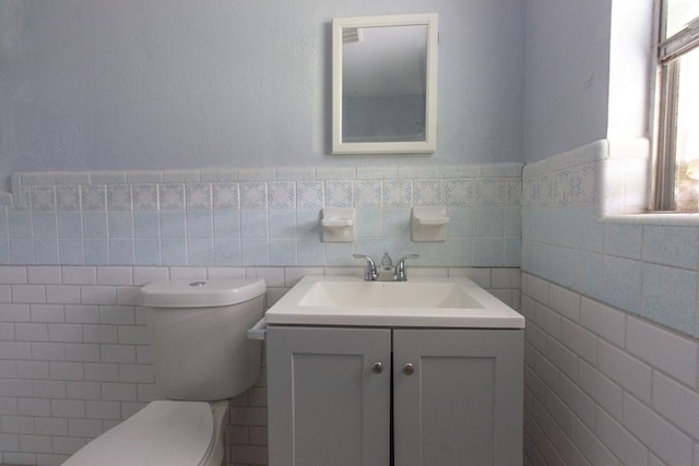 bathroom with vanity, toilet, and tile walls