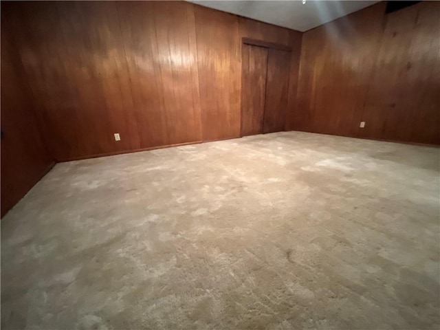 carpeted spare room with wooden walls