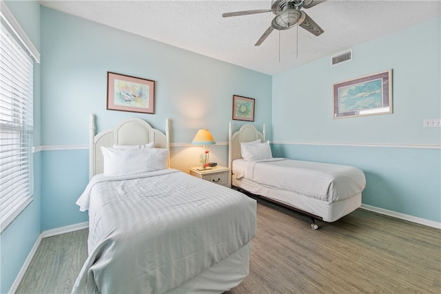 bedroom with hardwood / wood-style flooring, a textured ceiling, and ceiling fan